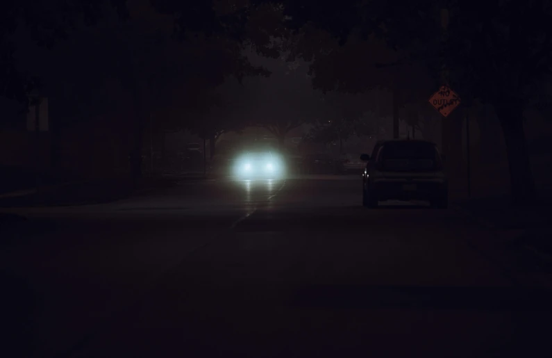 car driving down the street at night with headlights