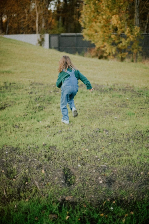 a girl in a green sweatshirt jumps in the grass