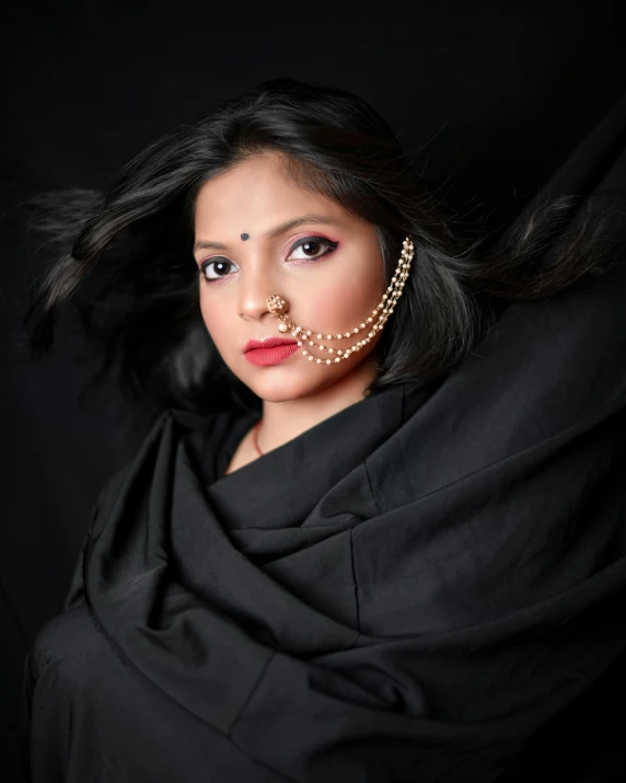 a woman in black scarf wearing a nose chain