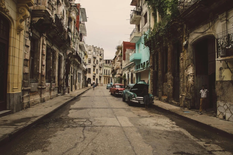 an old car sits parked on the side of an empty street