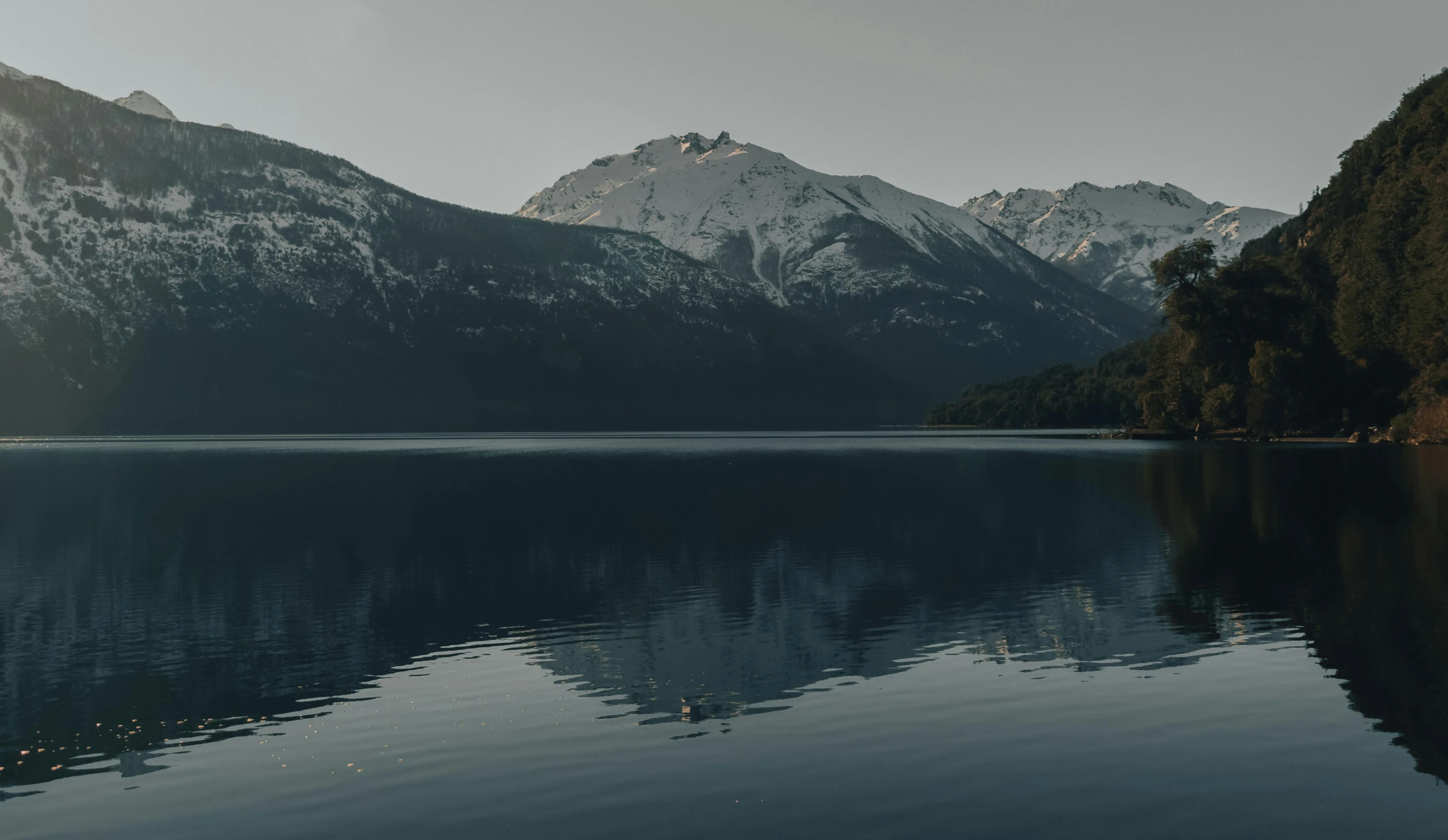 a mountain range rising up behind the water