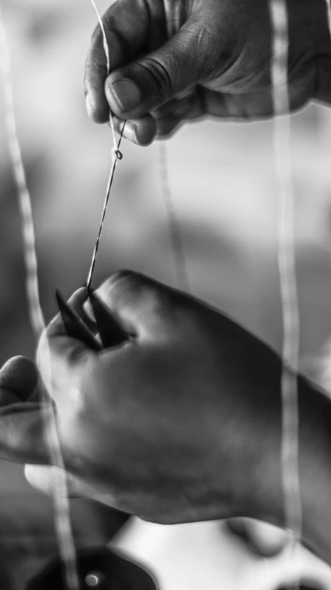 the hands are putting thread on nails that are still in the needles