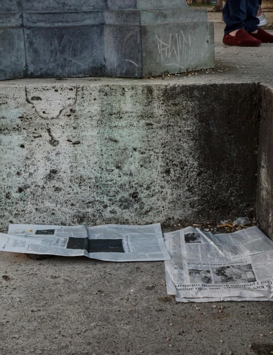 newspapers spread out on the ground next to graffiti