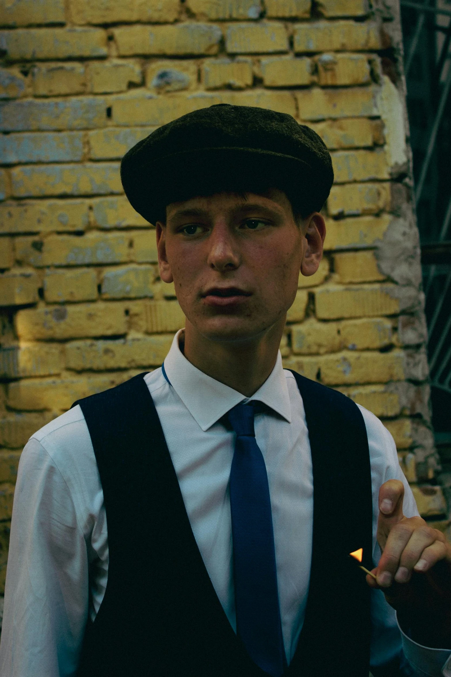 a boy wearing a suit and tie is standing by a brick wall