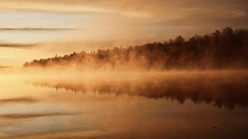 fog hangs over a lake at sunrise