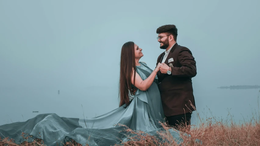 a man and woman pose for a portrait in front of water