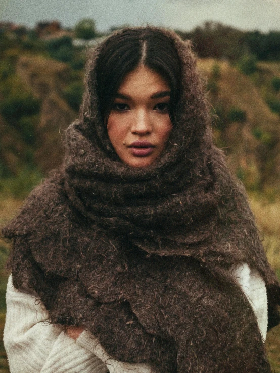 a woman with black hair is wearing a brown shawl