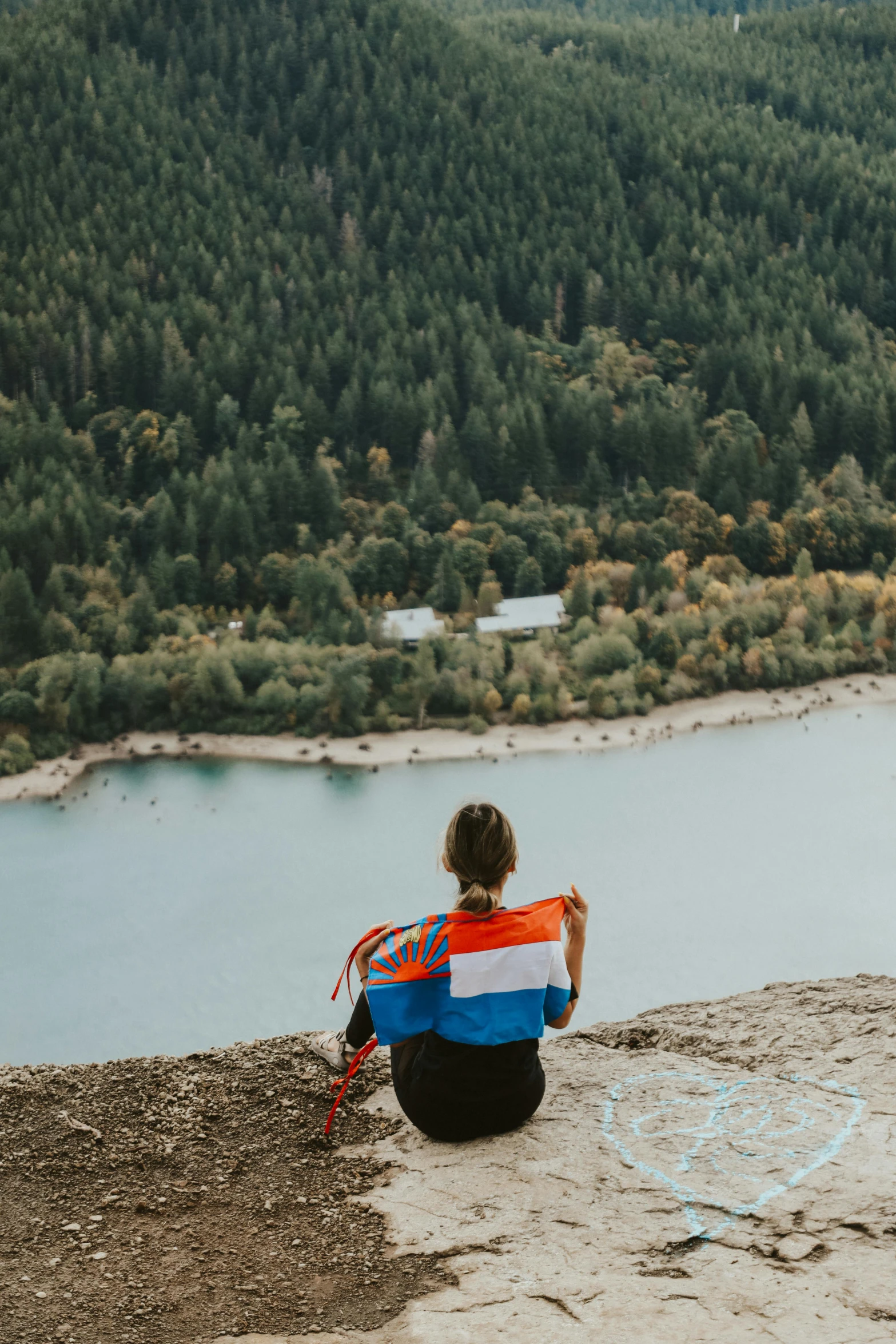 the woman sits alone at the edge of the cliff