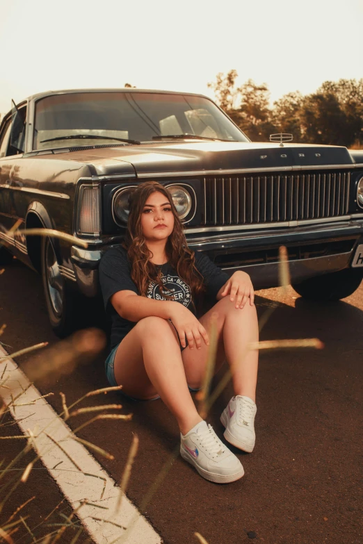 a girl sits in front of her car