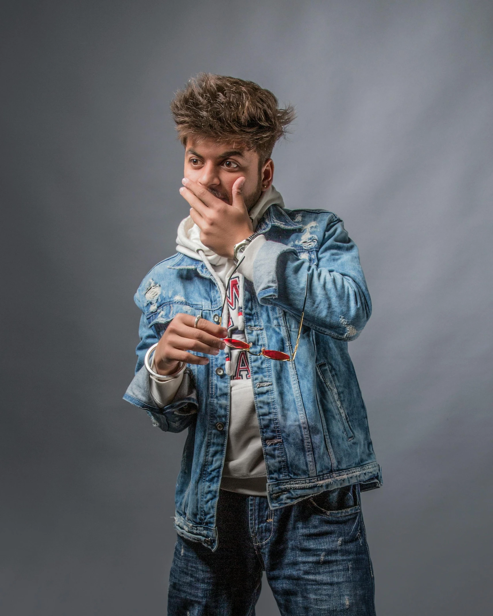 a young man in a jean jacket making a finger gesture