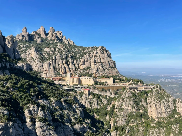 a view of some large rocky formations with trees and buildings