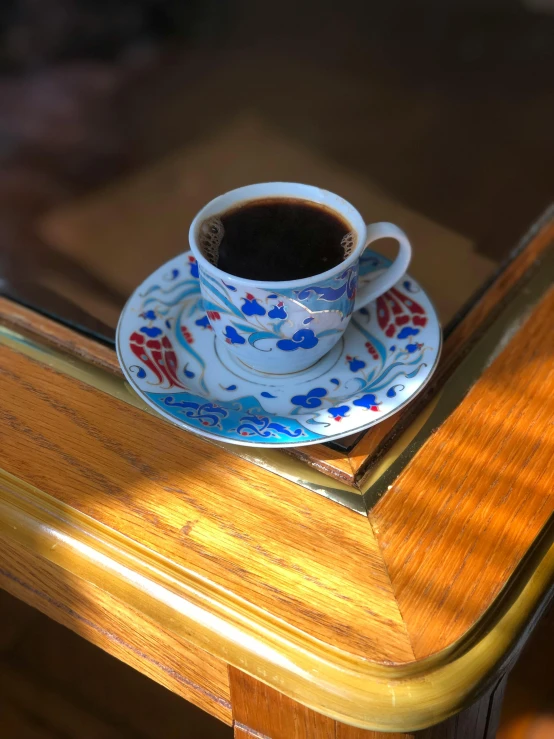 there is a cup of coffee on a plate on a desk