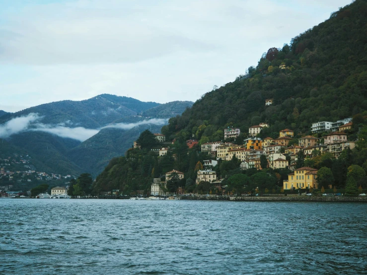 a mountain side village sits on the edge of a body of water