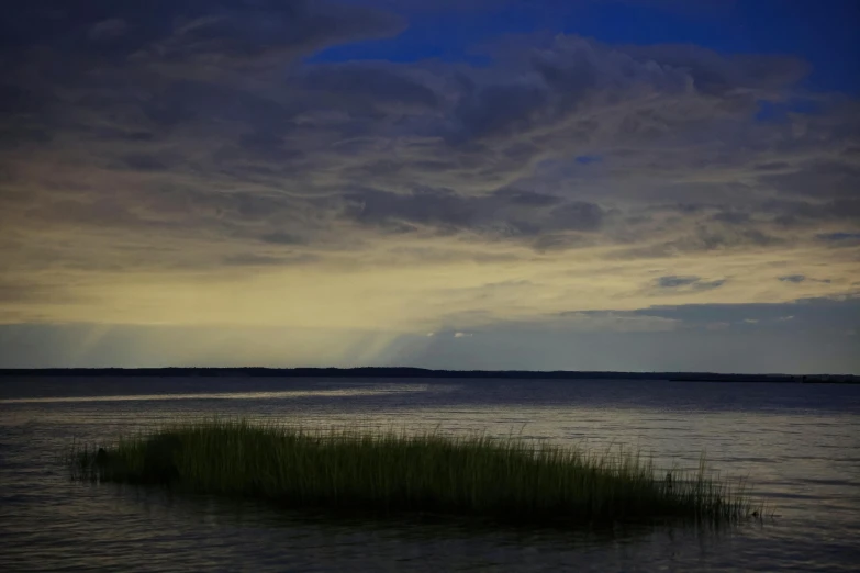 the sky is really cloudy as a long island stands in the water