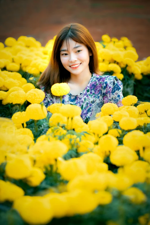 a girl smiles behind a bunch of yellow flowers