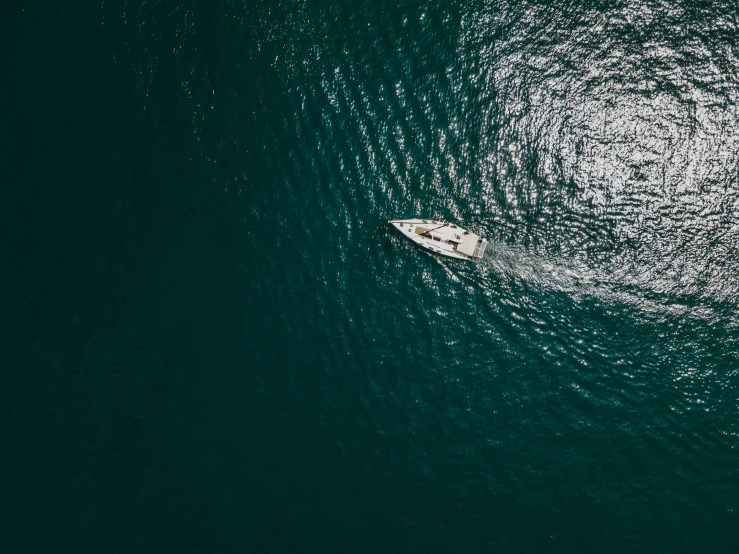 an overhead view of a small white boat on the ocean