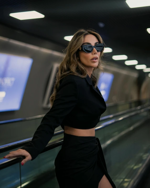 a woman is standing on an escalator in a dark skirt