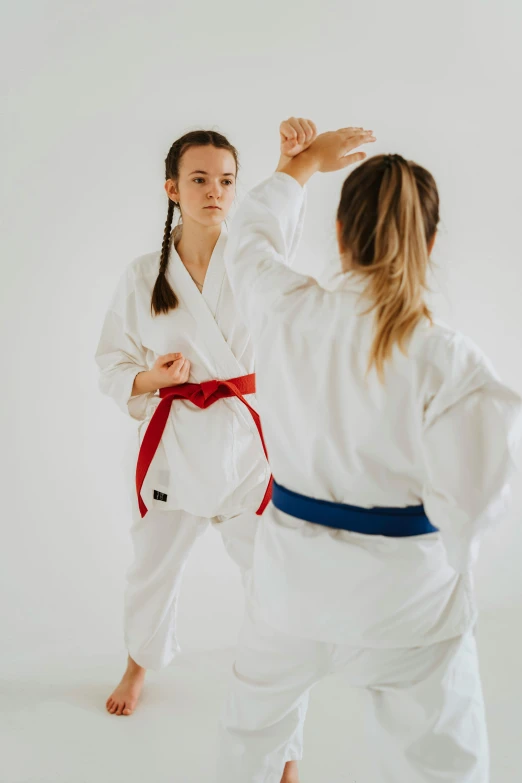a girl in white is doing karate with her mother