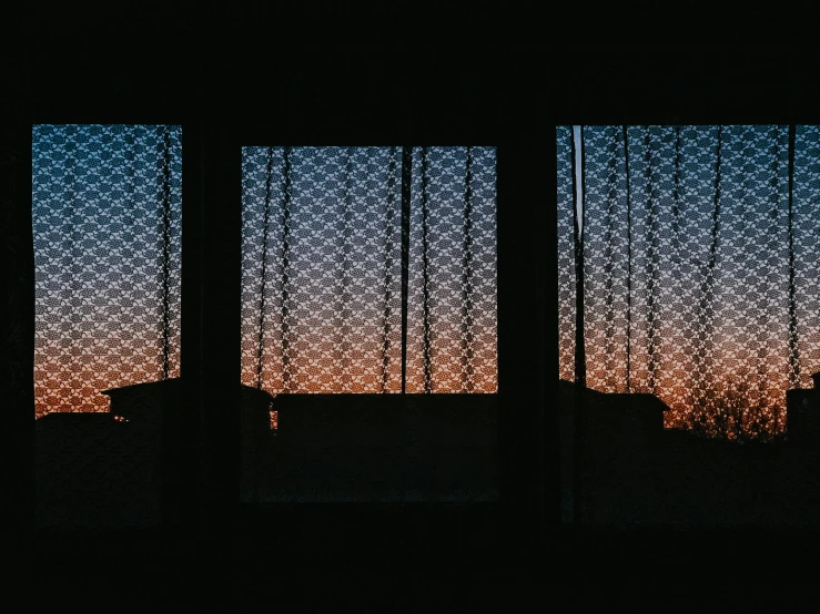 silhouette of a fenced in building with the sun setting