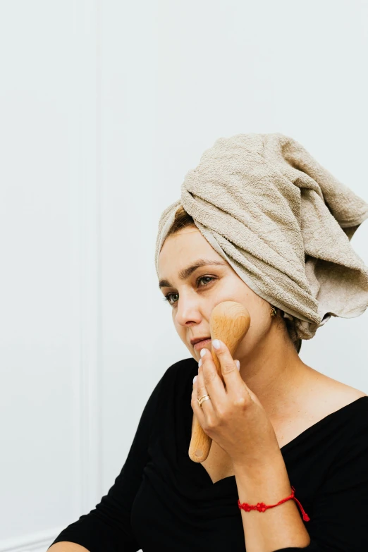 a woman holding a wooden spoon and looking at her face