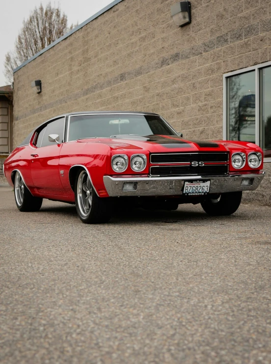 a classic red muscle car is parked in front of a building