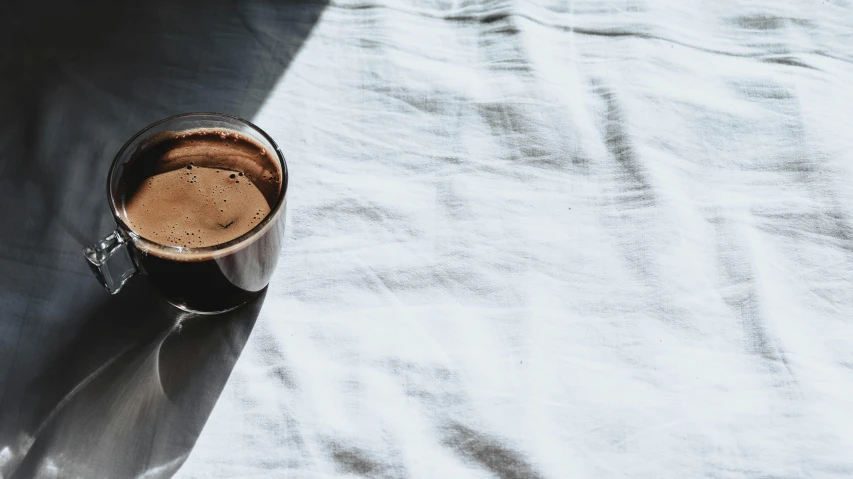 a mug of coffee is on a plain surface