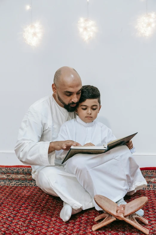 a man sitting down next to a  who is reading the book