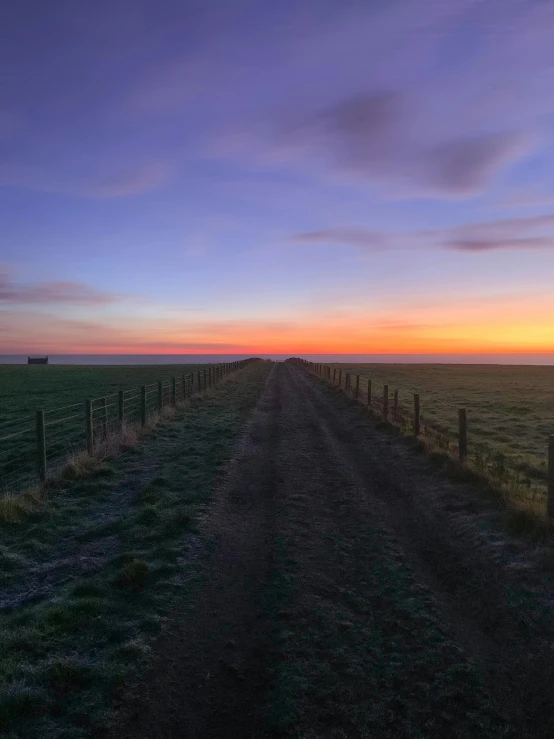 the sunset behind the field with a lone bench