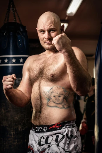 a man with a tattooed face, standing next to an punching bag