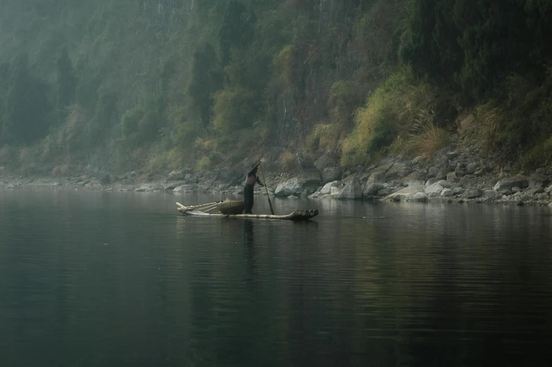 a person stands on a canoe in a mountain lake