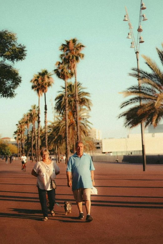 a man and woman walk with a dog