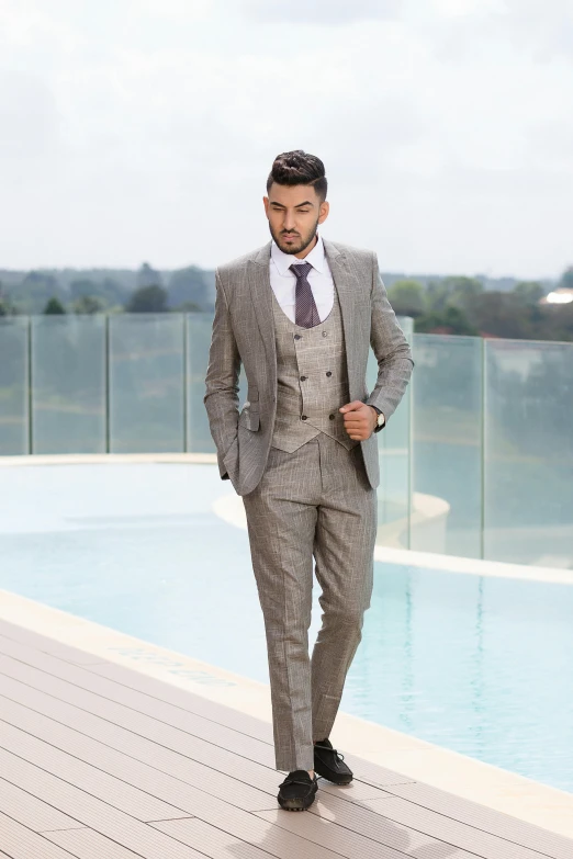 man in grey suit standing on the side of a swimming pool