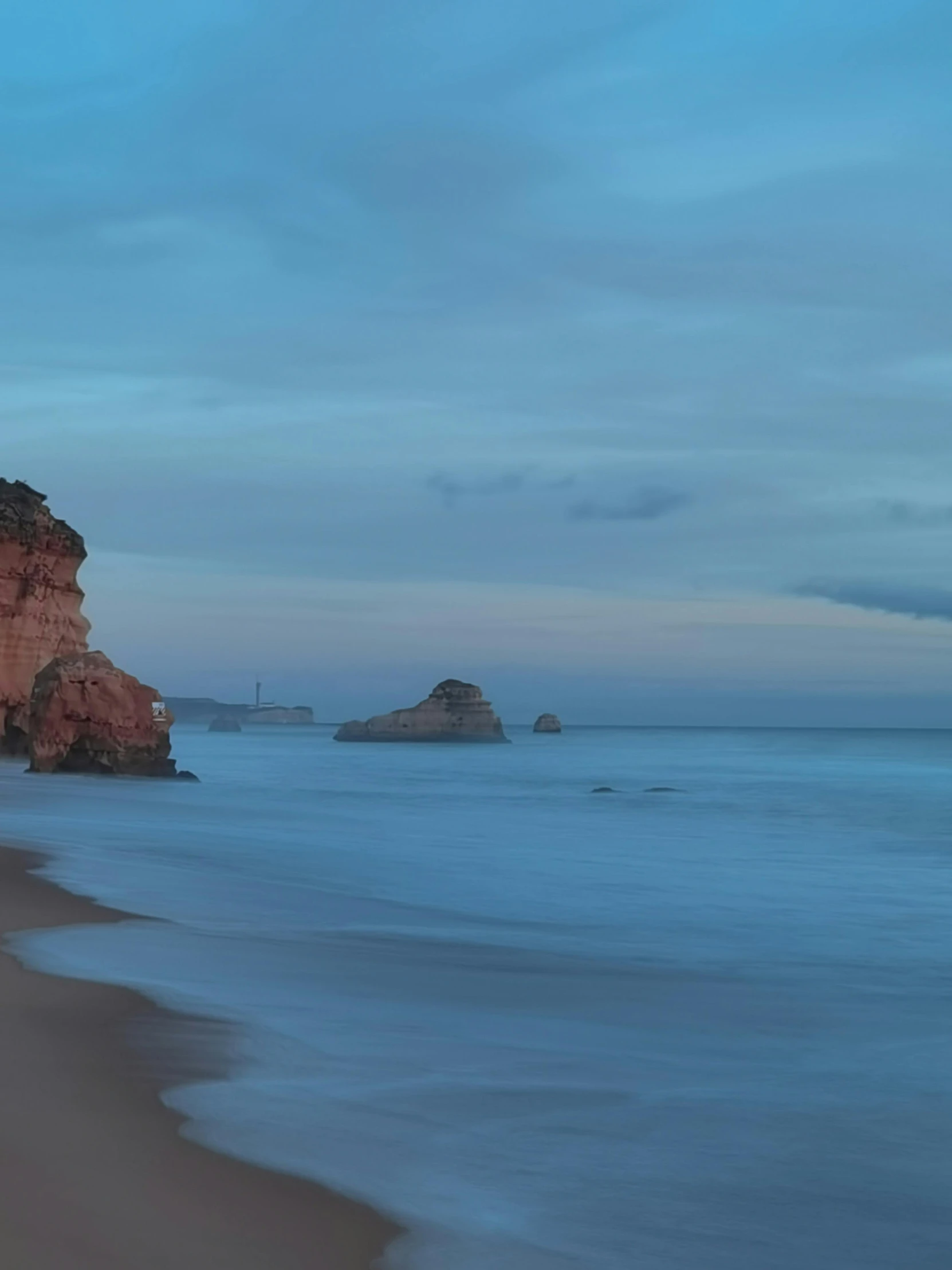 an empty beach is illuminated by the dusk