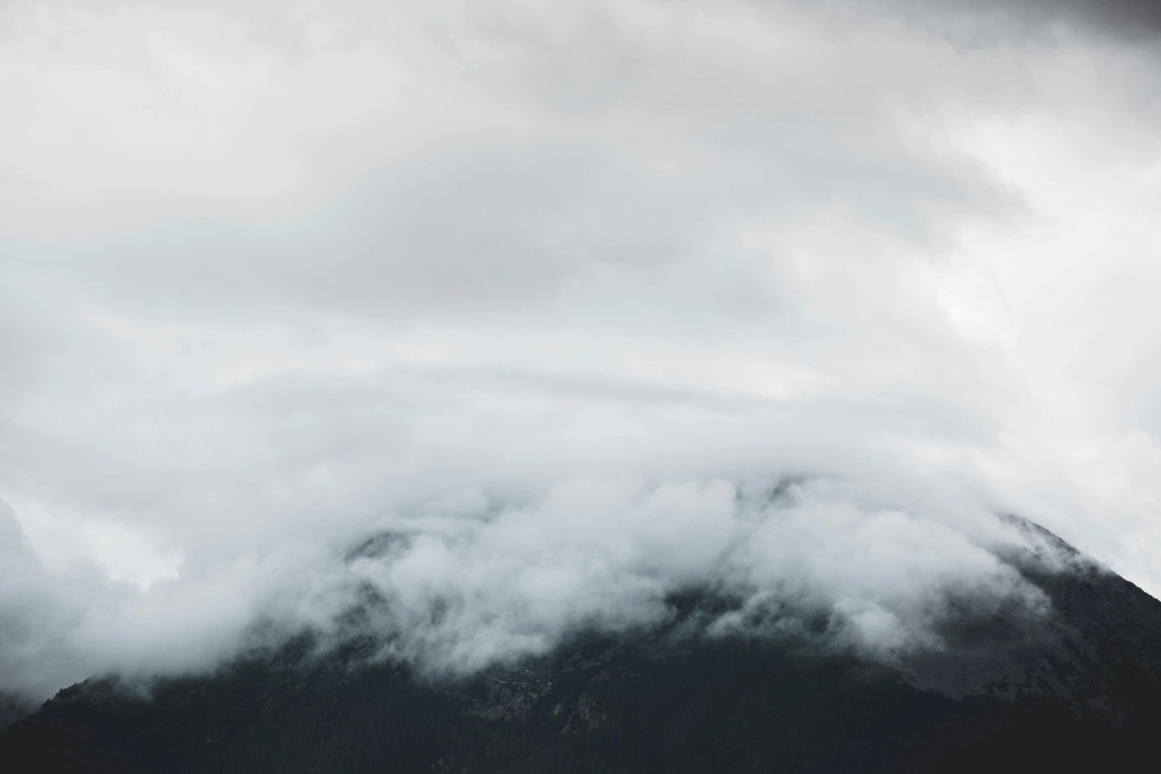 a mountain covered in clouds with a skier on top