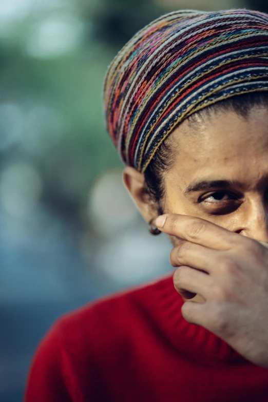 an older man wearing a head scarf with his hands on his face