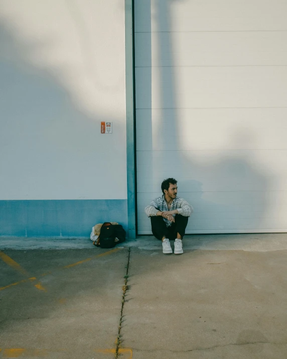 a man sitting down with a backpack on the side