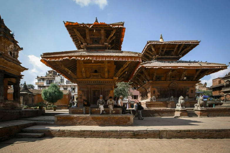 some people sitting and standing around a small building