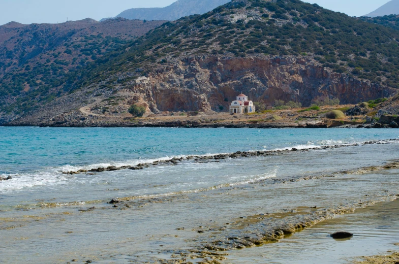 a house on the coast with a mountain in the background