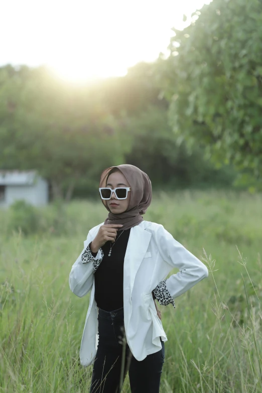 the woman wearing a headscarf is posing in tall grass