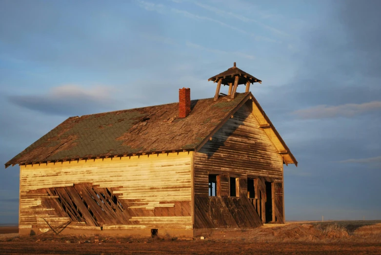 an old barn with a bell tower sitting on the grass