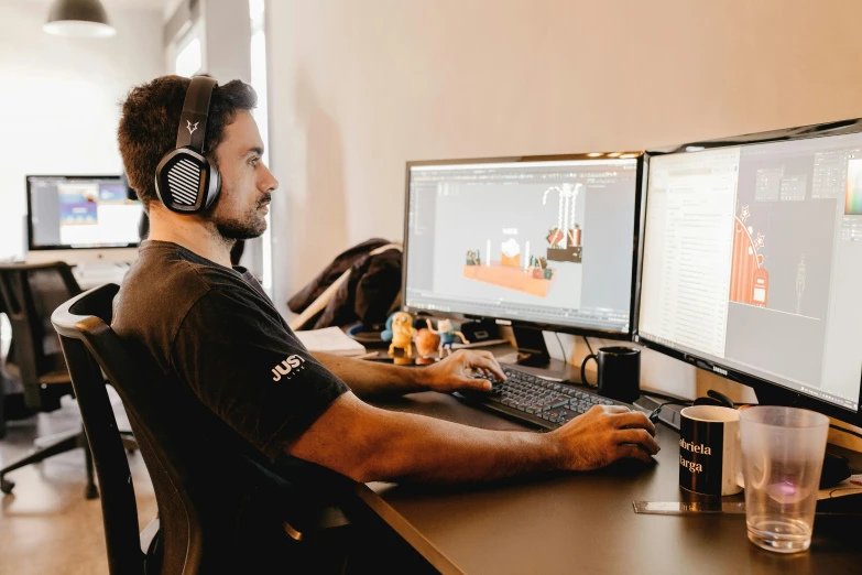 man sitting in front of two monitors showing multiple monitors