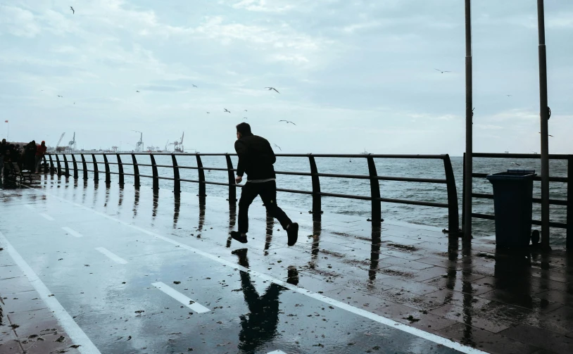 two people walking in the rain near an ocean