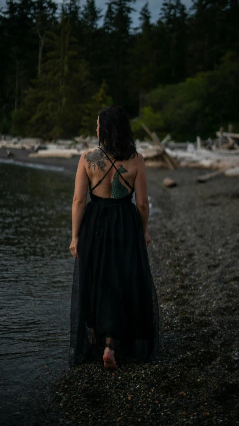 the back of a woman wearing a dress on top of a beach