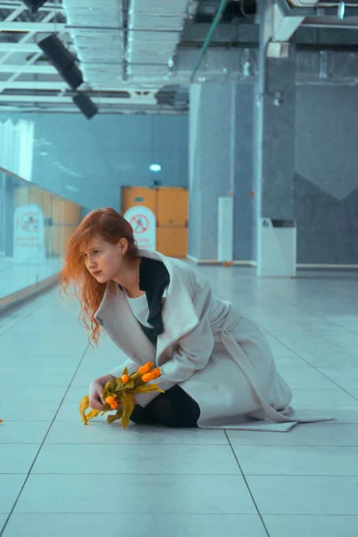 a woman in a trench jacket kneeling on the floor