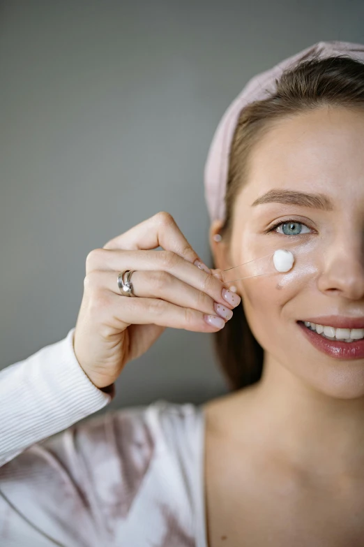 a woman holding an unmade piece of contact lens up to her face