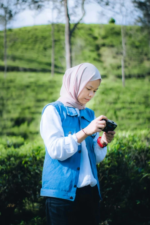 the woman in the hijab is standing on the green grass