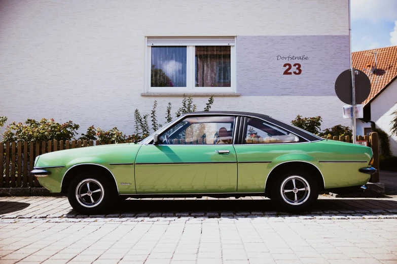 an old green car parked on the side of the road