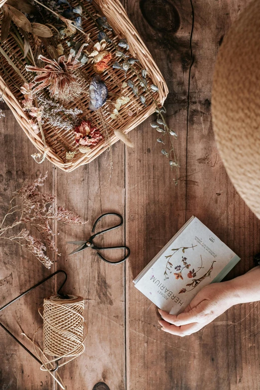 someone holding a book surrounded by crafts and paper