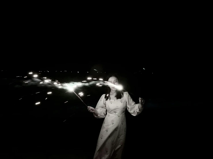 a woman holding a stick standing in the dark