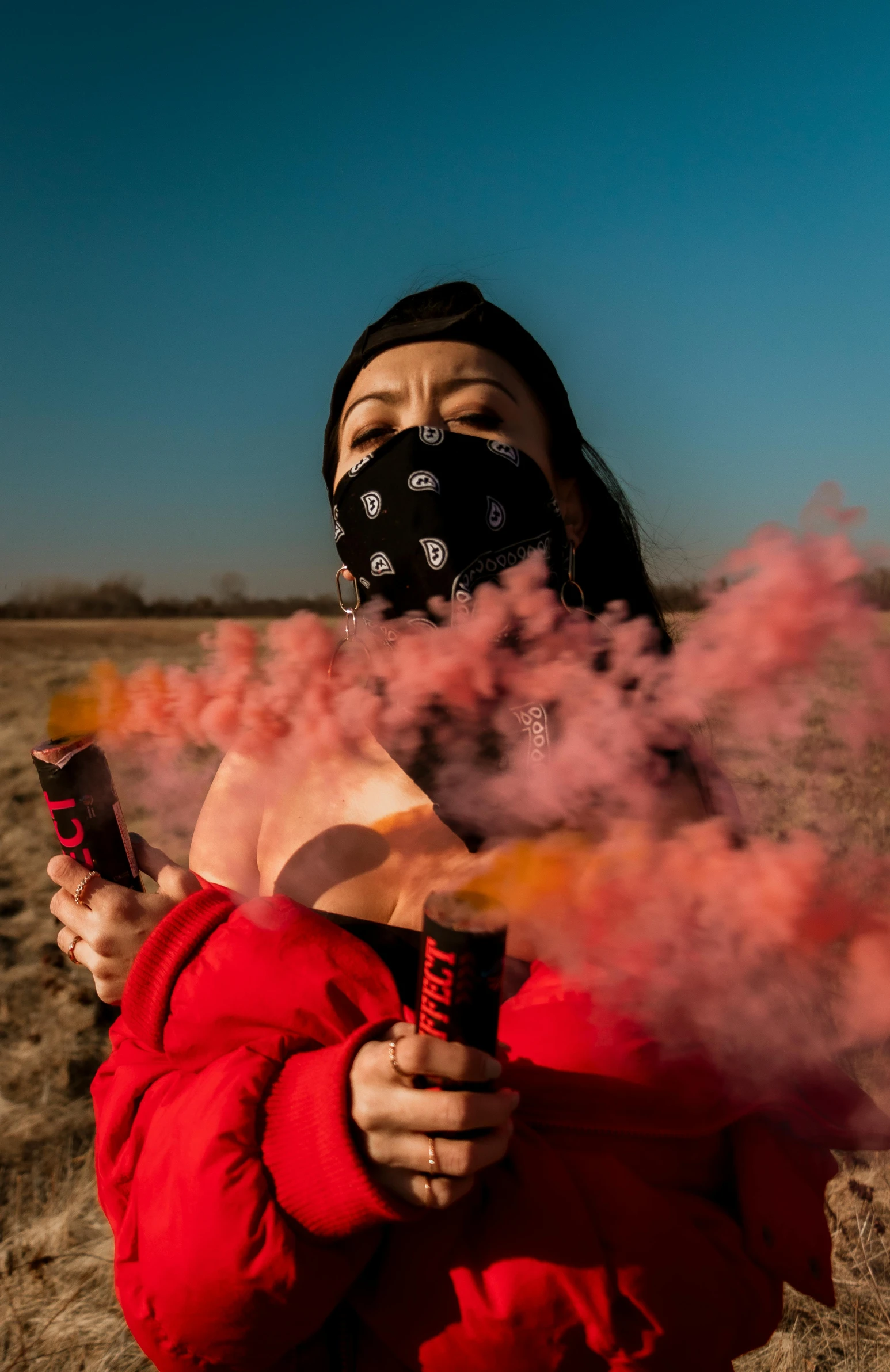 an oriental woman wearing a black mask smoking pink and orange smoke